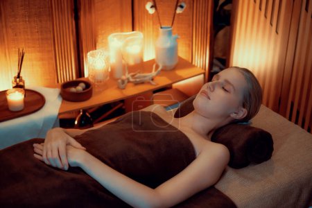 Photo for Caucasian woman customer enjoying relaxing anti-stress spa massage and pampering with beauty skin recreation leisure in warm candle lighting ambient salon spa at luxury resort or hotel. Quiescent - Royalty Free Image