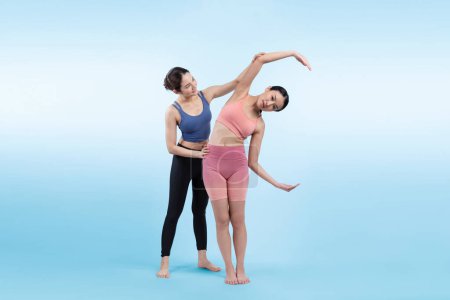 Téléchargez les photos : Femme asiatique en vêtements de sport faisant de l'exercice de yoga en pose debout avec son entraîneur ou son copain de yoga. Soins du corps sains et mode de vie de yoga de méditation en plan complet sur fond isolé. Vigoureux - en image libre de droit