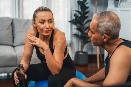 Photo for Athletic and sporty senior couple portrait in sportswear sitting on sofa as home exercise concept. Healthy fit body lifestyle after retirement. Clout - Royalty Free Image