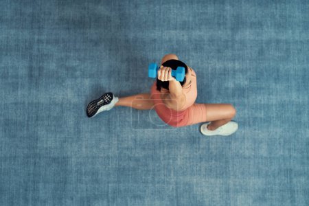 Photo for Top view home workout routine with carpet surface background, asian woman use dumbbell as weight training. Domestic fitness with sport equipment for strength and body workout session. Vigorous - Royalty Free Image