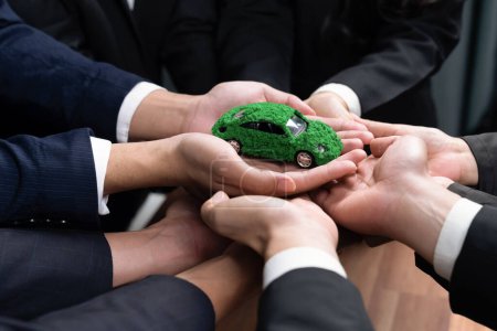 Téléchargez les photos : Les gens d'affaires détenant un modèle de voiture électrique en tant que partenariat de synergie d'entreprise s'unissent et prennent des mesures pour utiliser l'éco-transport afin de réduire les émissions de CO2 pour un avenir durable et plus vert. Charmante. - en image libre de droit