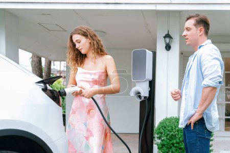 Photo for Happy and lovely couple with eco-friendly conscious recharging electric vehicle from EV home charging station. EV car technology utilized for residential home to future sustainability. Synchronos - Royalty Free Image