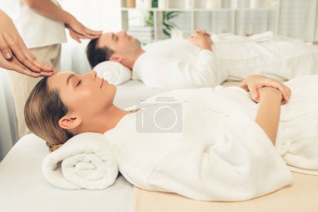 Foto de Pareja caucásica disfrutando de relajantes masajes anti-estrés en la cabeza y mimar belleza facial recreación de la piel de ocio en dayspa ambiente de luz moderna en el complejo de lujo o salón de spa del hotel. Silencioso. - Imagen libre de derechos