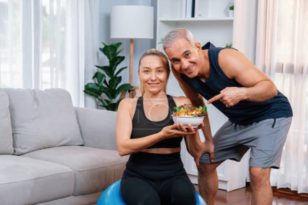 Photo for Healthy senior couple in sportswear with a bowl of fruit and vegetable. Healthy cuisine nutrition and vegan lifestyle for fitness body physique concept. Clout - Royalty Free Image