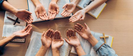 Photo for Cropped image of diversity people hand praying together at wooden church on bible book. Group of believer hold hand together faithfully. Concept of hope, religion, faith, god blessing. Burgeoning. - Royalty Free Image