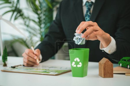 Photo for Businessman put paper waste on small tiny recycle bin in his office symbolize corporate effort on eco-friendly waste management by recycling for greener environment and zero pollution. Gyre - Royalty Free Image
