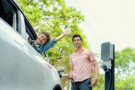 Photo for Family road trip vacation with electric vehicle, father and son recharge EV car with green and clean energy. Nature and travel with eco-friendly car for sustainable environment. Perpetual - Royalty Free Image