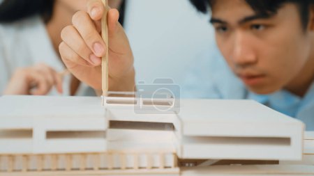 Photo for Closeup of young professional architect team work together to use pencil testing house model durability about house construction. Creative design and teamwork concept. Focus on hand. Immaculate. - Royalty Free Image