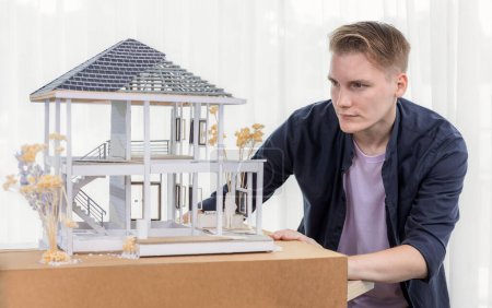 Téléchargez les photos : Architecte concepteur examinant le modèle de cadre de maison sans mur, remue-méninges design intérieur et idée d'amélioration avec l'échelle réelle de la maison. Professionnel et créativité dans la conception architecturale. Étiquetage - en image libre de droit