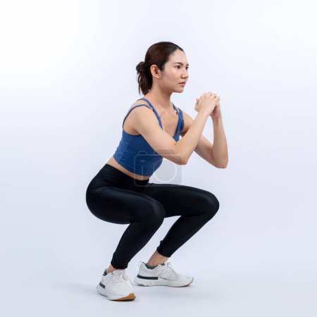 Photo for Vigorous energetic woman doing exercise. Young athletic asian woman strength and endurance training session as squat workout routine session. Full body studio shot on isolated background. - Royalty Free Image