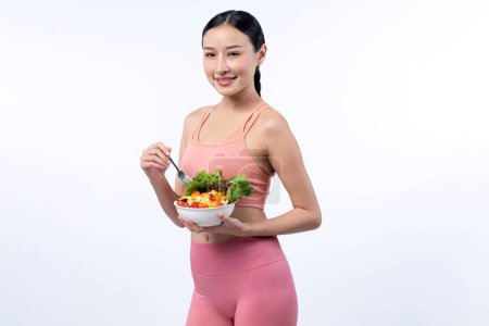 Téléchargez les photos : Jeune femme asiatique sportive en tenue de sport tenant saladier remplir avec vibrant de fruits et légumes. Mode de vie corporel naturel jeune et en forme avec équilibre nutritionnel sur fond isolé. Vigoureux - en image libre de droit