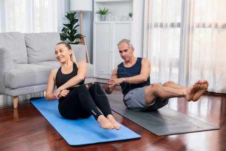 Photo for Athletic and sporty senior couple engaging matt exercising and doing crunch together at home exercise as concept of healthy fit body lifestyle after retirement. Clout - Royalty Free Image