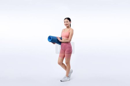 Téléchargez les photos : Jeune femme asiatique attrayant portrait en vêtements de sport avec tapis d'exercice. Exercice sain et routine d'entraînement concept de mode de vie. Studio a tourné en arrière-plan isolé. Vigoureux - en image libre de droit