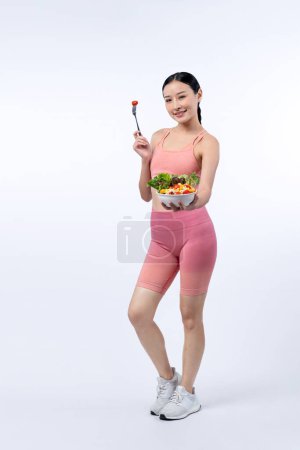 Téléchargez les photos : Jeune femme asiatique sportive en tenue de sport tenant saladier remplir avec vibrant de fruits et légumes. Mode de vie corporel naturel jeune et en forme avec équilibre nutritionnel sur fond isolé. Vigoureux - en image libre de droit