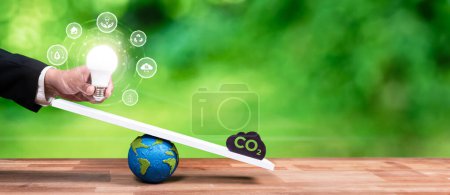 Téléchargez les photos : Homme d'affaires équilibre ampoule à l'échelle avec icône d'émission de CO2, démontrer l'engagement ESG et l'idée conservatrice de l'environnement à la réduction du carbone grâce à la technologie de l'énergie propre. Dépendance au panorama - en image libre de droit