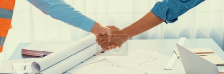 Photo for Construction engineer handshake with businessman contractor over architecture design blueprint on meeting table. Architect and engineer shake hand after successful cooperation teamwork. Insight - Royalty Free Image