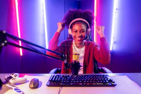 Photo for Host channel of gaming streamer, African girl taking, typing with Esport skilled team player and viewers online game in neon color lighting room. Concept of cybersport indoor activities. Tastemaker. - Royalty Free Image