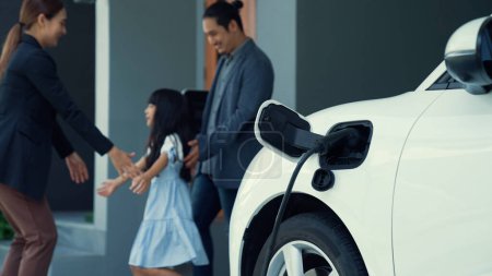 Photo for Concept of a progressive family with a home charging station for an electric vehicle, encouraging healthy and clean environment. The electric vehicle powered by sustainable, clean energy technology. - Royalty Free Image