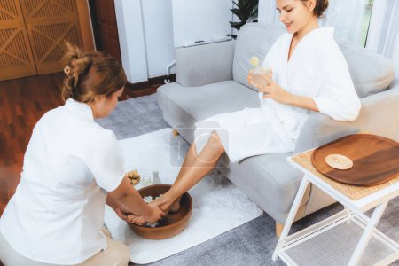Photo for Woman indulges in blissful foot massage at luxurious spa salon while masseur give reflexology therapy in gentle day light ambiance resort or hotel foot spa. Quiescent - Royalty Free Image