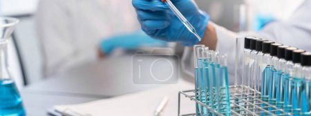 Photo for Group of dedicated scientist conduct chemical experiment in medical laboratory, carefully drop precise amount of liquid from pipette into test tube for vaccine drug or antibiotic development. Neoteric - Royalty Free Image