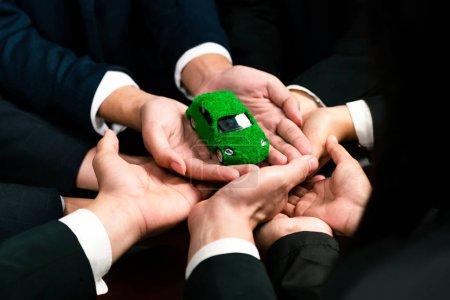 Foto de Los empresarios que sostienen el modelo de coche EV como asociación de sinergia empresarial se unen y toman medidas para utilizar el ecotransporte para reducir las emisiones de CO2 para un futuro sostenible y más verde. Pintoresco - Imagen libre de derechos