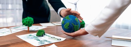 Photo for Business people holding paper earth together over office table. Green corporate company implementing eco-friendly policy to reduce CO2 emission and conserve green environment concept. Trailblazing - Royalty Free Image