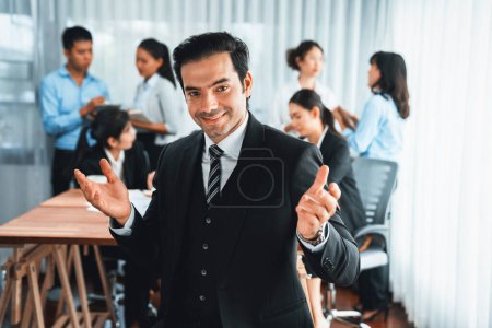 Téléchargez les photos : Portrait d'un homme d'affaires heureux regardant la caméra avec un fond flou de mouvement du mouvement des gens d'affaires dans une réunion d'affaires dynamique. Habillement - en image libre de droit