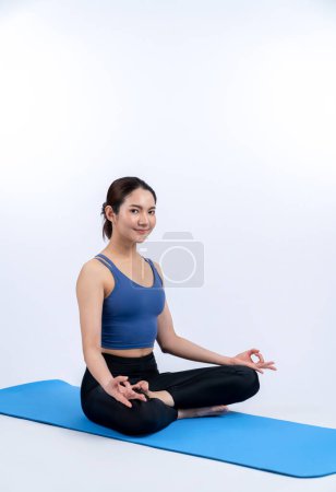 Photo for Asian woman in sportswear doing yoga exercise on fitness mat as her workout training routine. Healthy body care and calm meditation in yoga lifestyle in full body shot on isolated background. Vigorous - Royalty Free Image