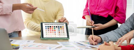 Téléchargez les photos : Un portrait de la créativité graphiste équipe choisir la couleur appropriée pour le projet en utilisant un ordinateur portable sur la table avec l'équipement et la conception d'outils disperser autour au bureau moderne. Gros plan. Varié. - en image libre de droit