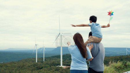 Photo for Concept of progressive happy family enjoying their time at the wind turbine farm. Electric generator from wind by wind turbine generator on the country side with hill and mountain on the horizon. - Royalty Free Image