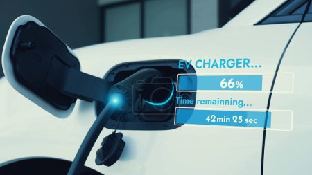Téléchargez les photos : Chargeur EV de la station de charge à domicile branché et rechargeant la voiture électrique affichant l'hologramme d'état de la batterie numérique. Infrastructure énergétique résidentielle intelligente et futuriste. Pertinence - en image libre de droit