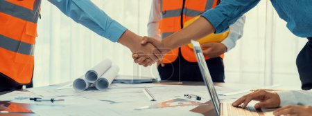 Photo for Construction engineer handshake with businessman contractor over architecture design blueprint on meeting table. Architect and engineer shake hand after successful cooperation teamwork. Insight - Royalty Free Image