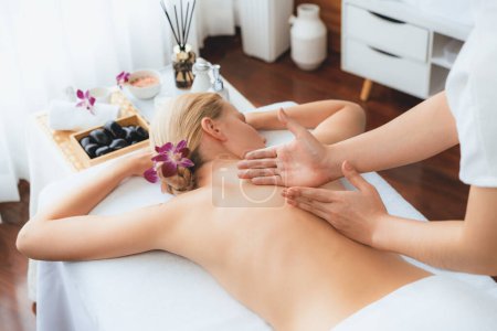 Photo for Caucasian woman customer enjoying relaxing anti-stress spa massage and pampering with beauty skin recreation leisure in day light ambient salon spa at luxury resort or hotel. Quiescent - Royalty Free Image