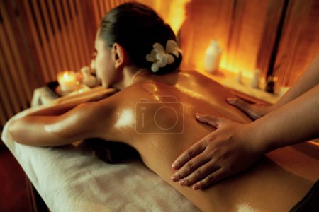Photo for Caucasian woman customer enjoying relaxing anti-stress spa massage and pampering with beauty skin recreation leisure in warm candle lighting ambient salon spa at luxury resort or hotel. Quiescent - Royalty Free Image