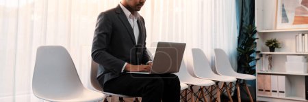Photo for Job applicant waiting for interview in waiting room alone with empty chair on the corridor while applying on job application form. Modern employment and career seeker opportunity concept. Trailblazing - Royalty Free Image