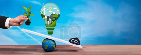 Photo for Businessman balance light bulb on scale with CO2 emission icon, demonstrate ESG commitment and environmental conservative idea to carbon reduction through clean energy technology. Panorama Reliance - Royalty Free Image