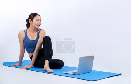 Photo for Young asian woman in sportswear stretching before fitness exercise following instruction from online video. Body workout with healthy athletic woman warming up on isolated background. Vigorous - Royalty Free Image