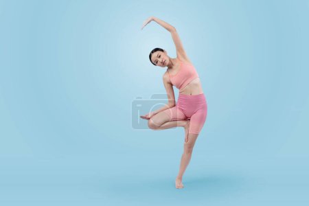 Photo for Asian woman in sportswear doing yoga exercise in standing pose on fitness as her workout training routine. Healthy body care and meditation yoga lifestyle in full shot on isolated background. Vigorous - Royalty Free Image