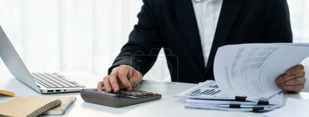 Photo for Corporate accountant use calculator to calculate and maximize tax refunds and improve financial performance based on financial data report. Modern business accounting in panorama. Shrewd - Royalty Free Image