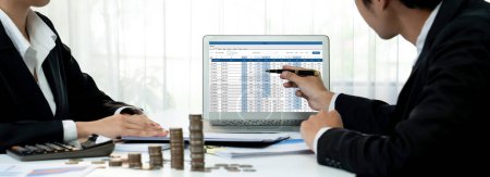Photo for Corporate accountant use accounting software on laptop to calculate and maximize tax refunds and improve financial performance with business investment concept of growth stack coin in panorama. Shrewd - Royalty Free Image