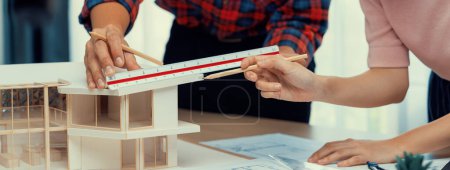 Photo for Smart architect engineer and interior designer working together and measuring house model by using ruler on meeting table with blueprint and architectural equipment. Teamwork concept. Burgeoning. - Royalty Free Image