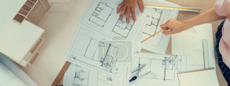 Photo for Blueprint architectural document scatter around on meeting table while professional architect engineer hand pointing at blueprint. Creative design teamwork discussion concept. Top view. Burgeoning. - Royalty Free Image