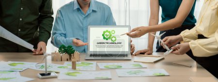 Téléchargez les photos : Logo de la technologie verte affiché sur l'ordinateur portable vert d'affaires tandis que l'équipe d'affaires présentant le design vert au client. Environnement ESG gouvernance sociale et concept éco-conservateur. Gros plan. Délimitation - en image libre de droit