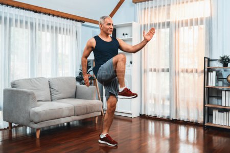 Photo for Athletic and sporty senior man make running pose at home. Healthy fit body lifestyle as home workout exercise concept after retirement. Clout - Royalty Free Image