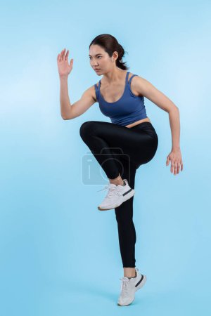 Foto de Vista lateral joven atlética mujer asiática en la ejecución de la postura en el estudio de tiro sobre fondo aislado. Búsqueda de la forma saludable cuerpo físico y ejercicio cardiovascular concepto de estilo de vida de ejercicio. Vigoroso - Imagen libre de derechos