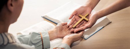 Photo for Close-up women prayer deliver holy bible book and holy cross to young believer. Spreading religion symbol. Concept of hope, religion, christianity and god blessing. Warm background. Burgeoning. - Royalty Free Image
