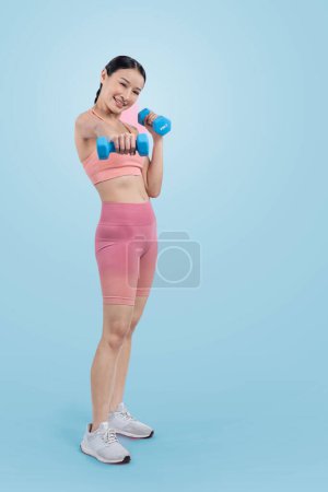 Foto de Mujer enérgica vigorosa haciendo ejercicio de levantamiento de pesas con mancuerna sobre un fondo aislado. Joven atlético asiático mujer fuerza y resistencia entrenamiento sesión como cuerpo entrenamiento rutina. - Imagen libre de derechos