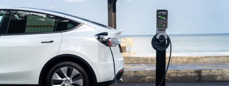 Photo for Electric car recharging battery at outdoor EV charging station for road trip or car traveling by the seascape, alternative and sustainable energy technology for eco-friendly car. Perpetual - Royalty Free Image