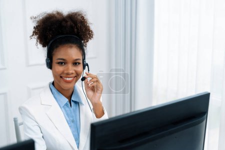 Téléchargez les photos : Femme d'affaires afro-américaine portant casque de travail dans le bureau pour soutenir client crucial à distance ou collègue. Le centre d'appels, le télémarketing, l'agent de soutien à la clientèle fournissent le service sur appel vidéo. - en image libre de droit