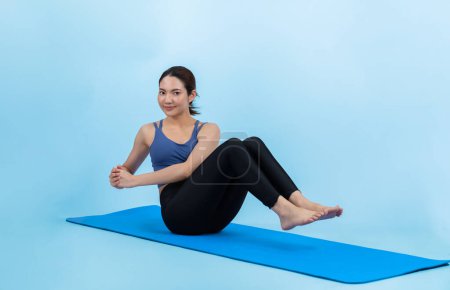 Photo for Asian woman in sportswear doing crunch on exercising mat as workout training routine. Attractive girl in pursuit of healthy lifestyle and fit body physique. Studio shot isolated background. Vigorous - Royalty Free Image